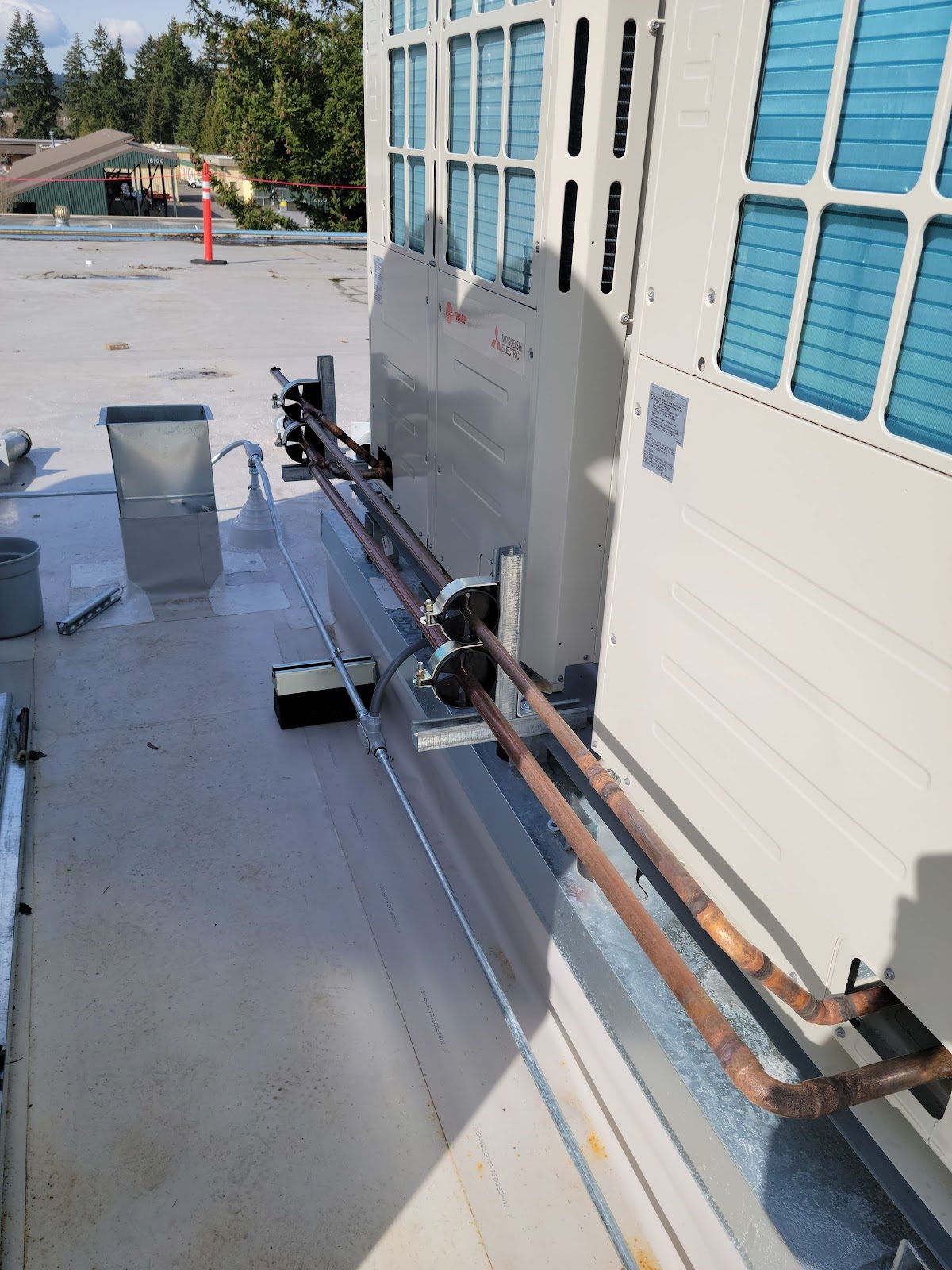 Copper refrigerant line set run cleanly along the roof of a commercial building in Pierce County