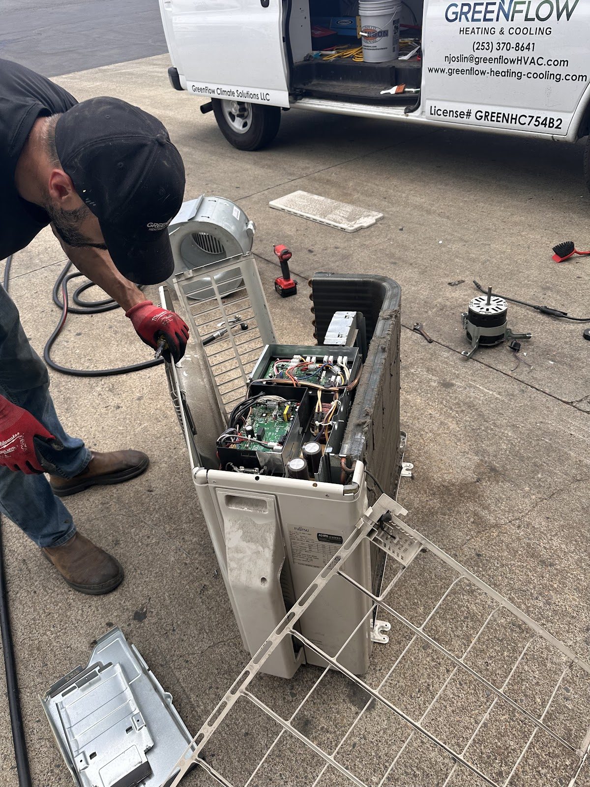GreenFlow technician working on an outdoor unit next to the branded GreenFlow service van