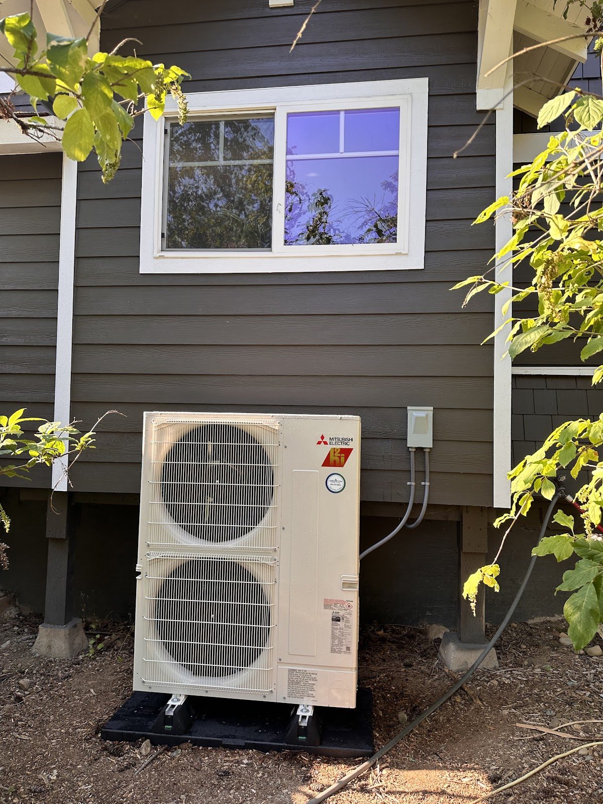 Mitsubishi outdoor heat pump condenser installed on side of a South Sound home