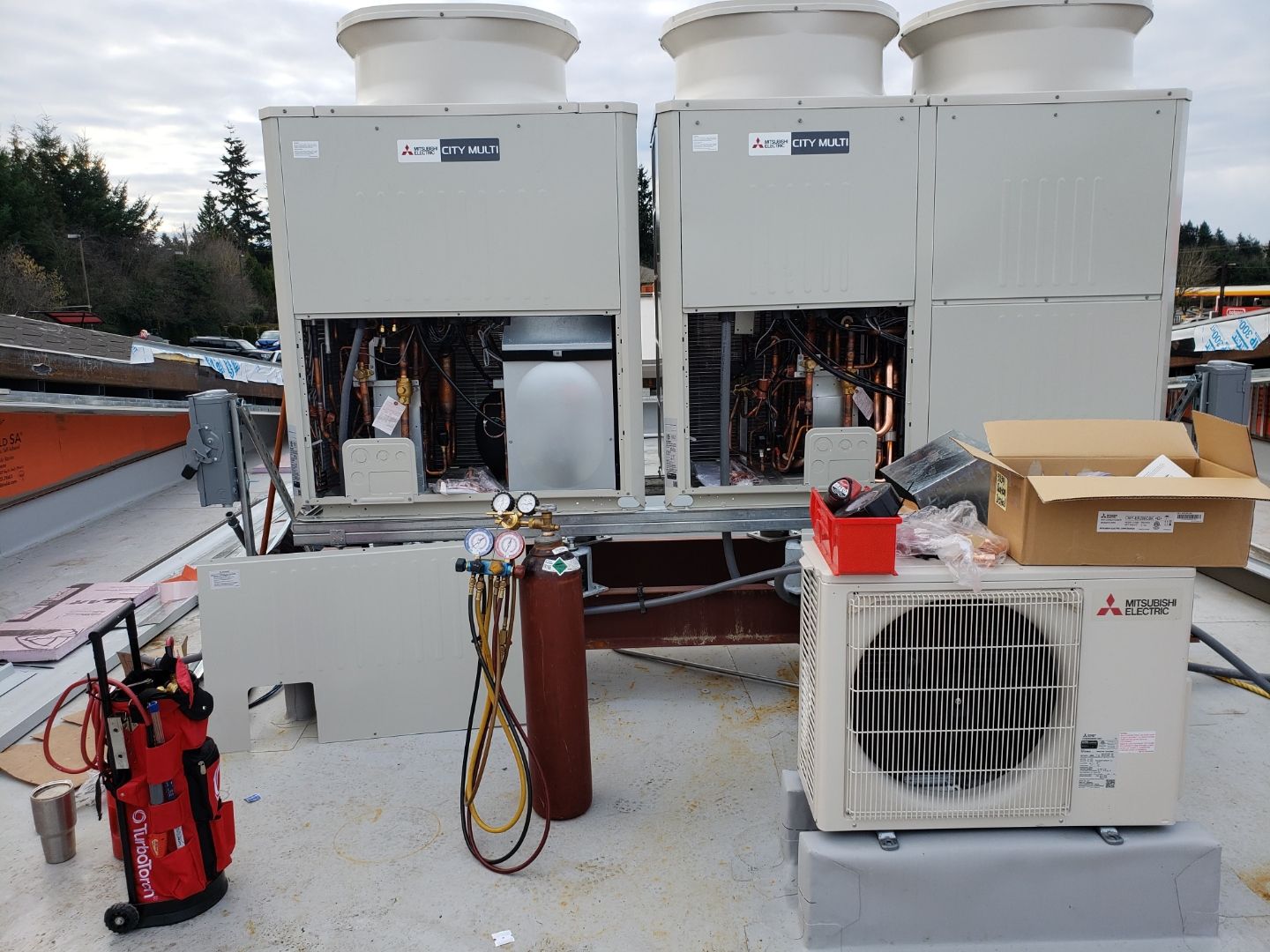 GreenFlow technician commissioning Mitsubishi City Multi VRF outdoor units on a commercial rooftop in Pierce County
