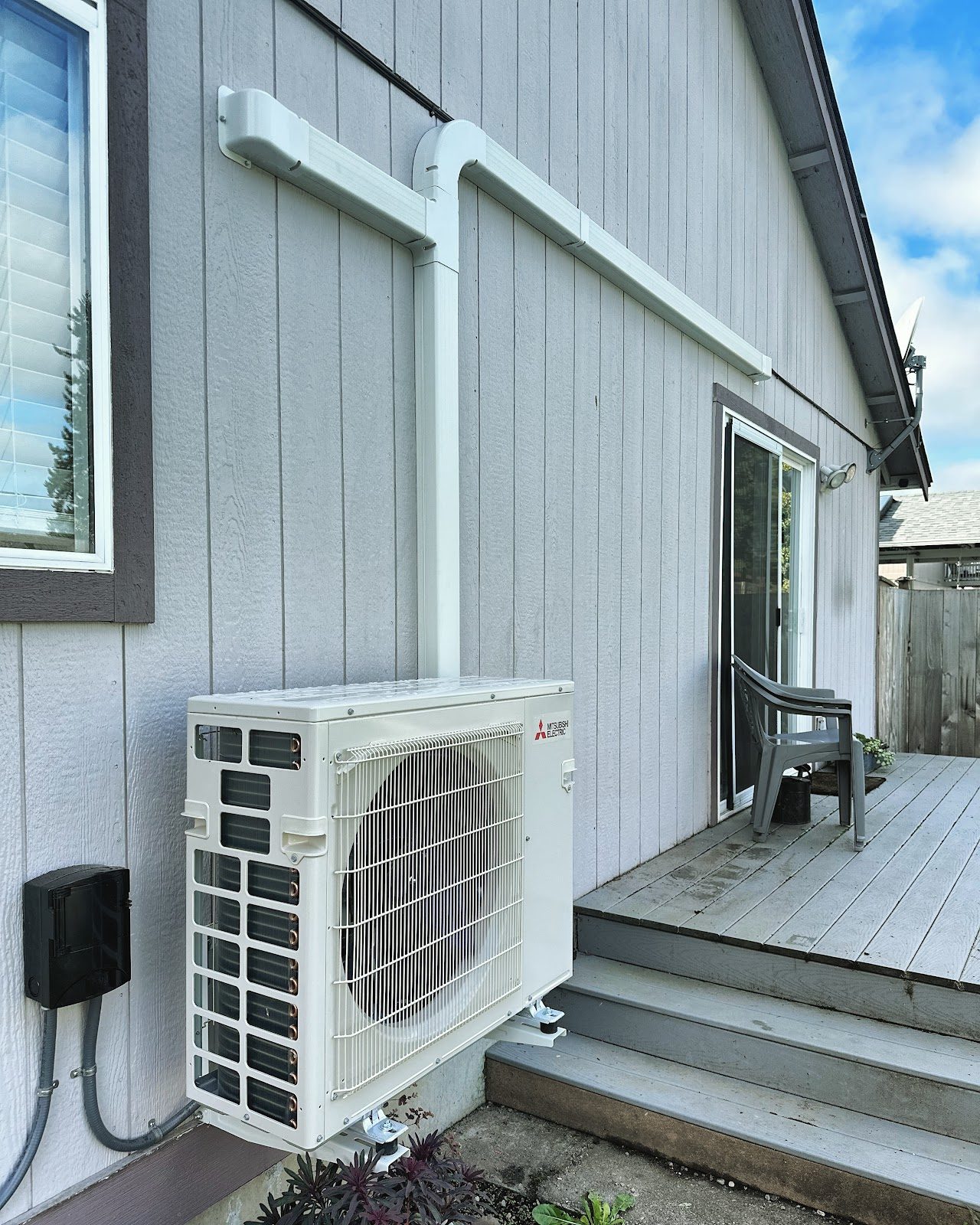 Mitsubishi ductless outdoor unit installed beside a deck at a Tacoma home